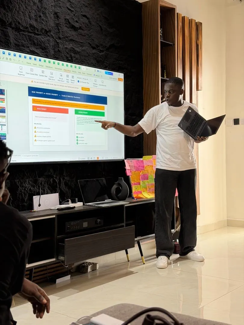 Ayodeji presenting a good prompt versus bad prompt lesson on a large screen